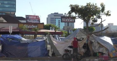 Los Angeles, CA USA - 15 Kasım 2021: Bir Sizzler restoranı, Şükran Günü yemeği için evsizler kampı reklamlarıyla çevrili