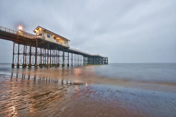 Nézd a strandtól egy brit Pier alkonyatkor Stock Kép