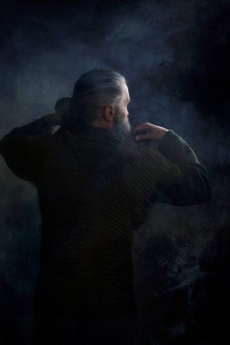 Viking savaşçısı dumanlı odada zincirli postaları kaldırıyor.