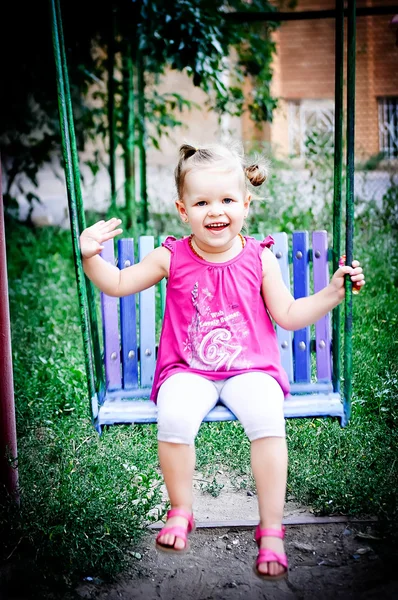 A little girl riding on a swing in the park — Stock Photo, Image