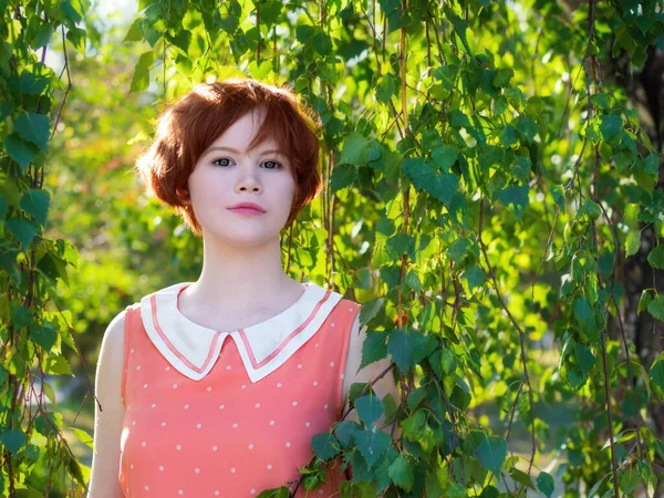 緑の葉の間に公園の赤い髪の幸せな女の子の肖像画 — ストック写真