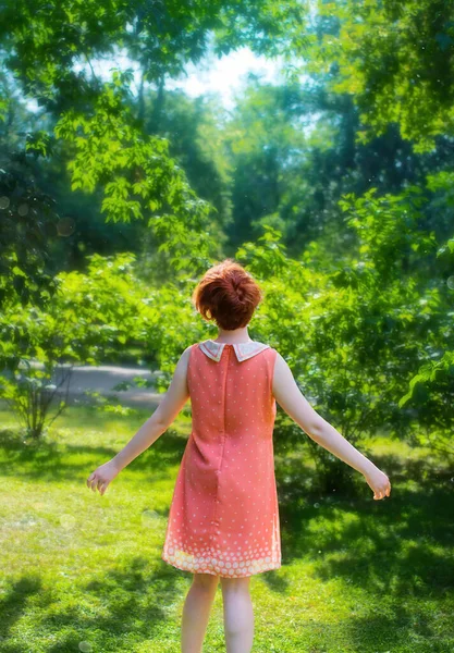 夏の公園で楽しみを持っている晴れた日の赤い髪の女の子 ストック写真