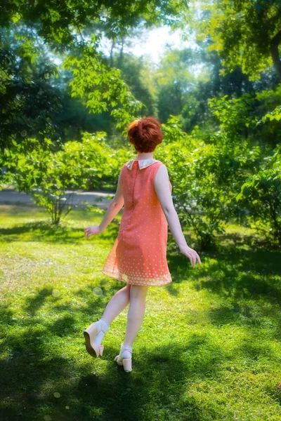 夏の公園で楽しみを持っている晴れた日の赤い髪の女の子 ストックフォト