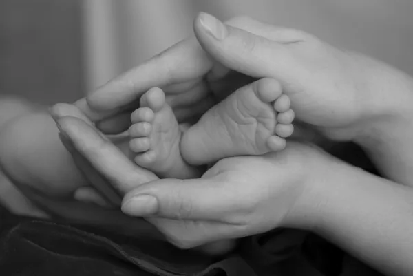 宝宝的脚，在妈妈的手 免版税图库图片