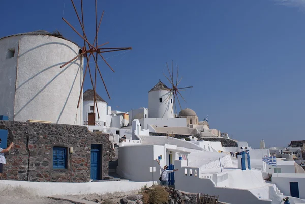 Moulins à vent traditionnels blancs à l'ancienne dans un village en terrasses Oia des Cyclades île de Santorin Grèce sur le fond bleu de la mer Égée et du ciel — Photo