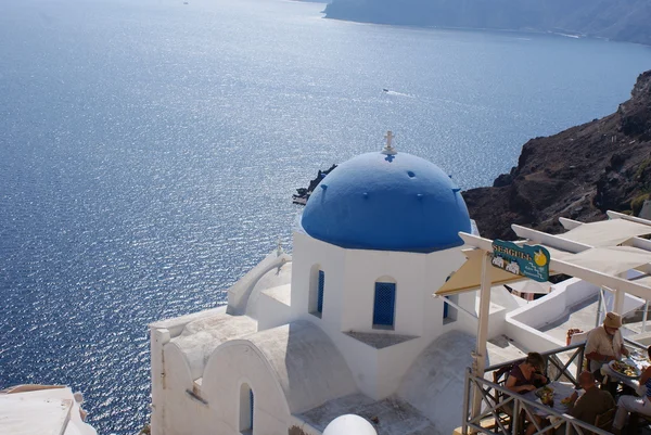Old-style white traditional windmills in terraced village Oia of Cyclades island Santorini Greece on the blue Aegean Sea and sky background