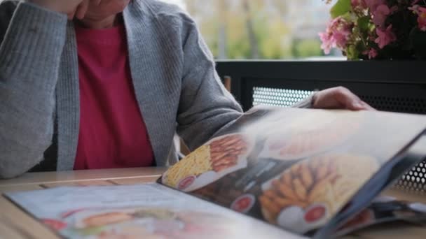 在餐馆或咖啡馆菜单中翻阅页面的妇女特写 — 图库视频影像