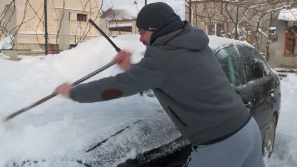 一个人把雪从车上抹去 冬天的时候 人在街上把雪从他的车上抹去 — 图库视频影像
