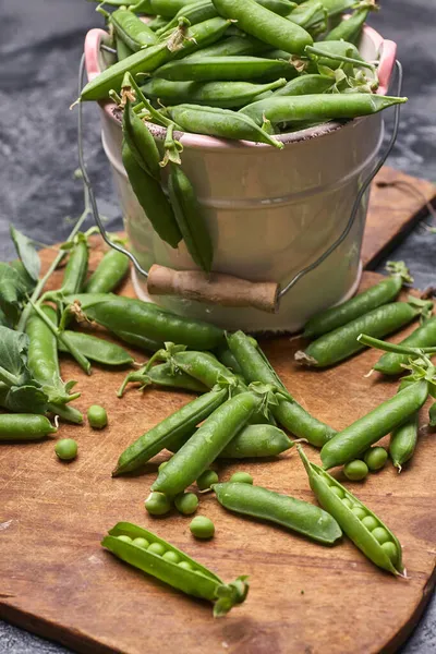 stock image Pods of green peas with leaves in bowl on wooden table