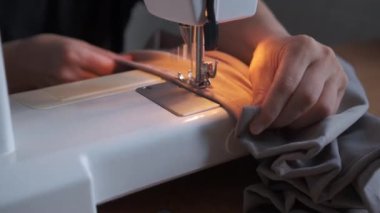 Dikiş makinesiyle dikiş diken genç bir kadının elleri.