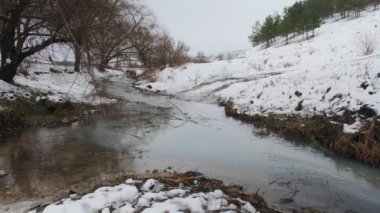 Kış nehri. Kirli su nehir kanalına bir borudan girer. Kumlu alt.