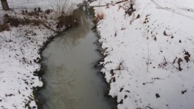 Kış nehri. Kirli su nehir kanalına bir borudan girer. Kumlu alt.