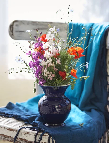 Natureza morta com flores silvestres frescas em vaso na cadeira vintage — Fotografia de Stock