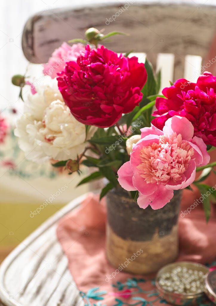 Still life with white and pink peonies in a old ceramic vase on vintaje chair