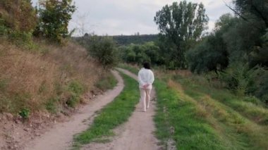 Genç esmer kadınlar köy yolunda rahatça yürürler.