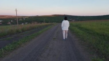 Genç esmer kadınlar köy yolunda rahatça yürürler.