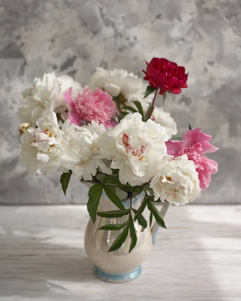 Bodegón con peonías blancas y rosadas en un jarrón blanco — Foto de Stock