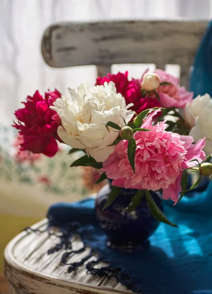 Natureza morta com peônias brancas e rosa em um vaso azul na cadeira de vintaje — Fotografia de Stock