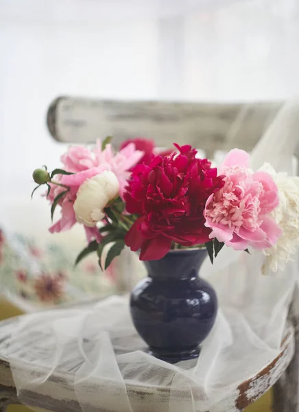 Natureza morta com peônias brancas e rosa em um vaso azul na cadeira de vintaje — Fotografia de Stock