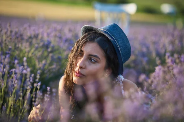 戴着帽子的年轻女子躺在薰衣草地里 — 图库照片