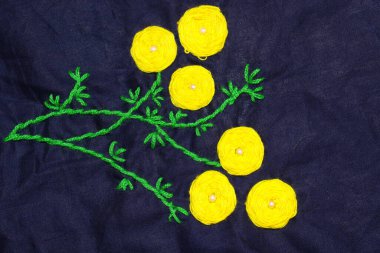 sarı ve yeşil renkli yünlü el işi kumaş üzerine daire şeklinde işlemeler.