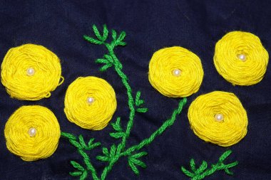 sarı ve yeşil renkli yünlü el işi kumaş üzerine daire şeklinde işlemeler.