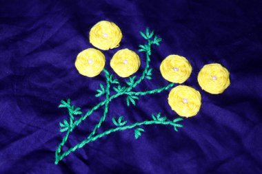 sarı ve yeşil renkli yünlü el işi kumaş üzerine daire şeklinde işlemeler.