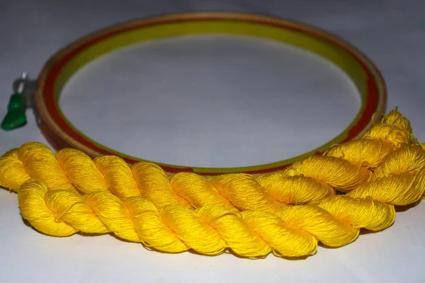 yellow colored wool yarn bunch with hand wood circle frame for embroidery