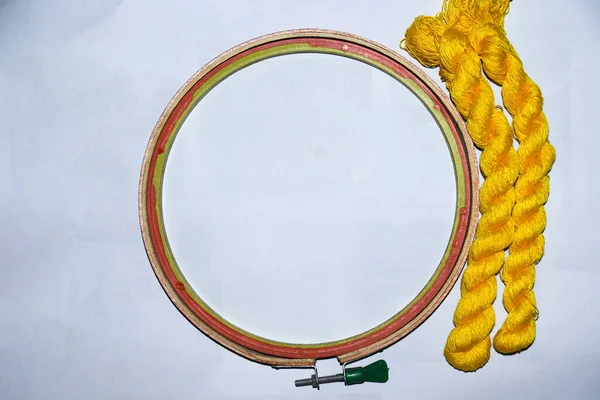 yellow colored wool yarn bunch with hand wood circle frame for embroidery