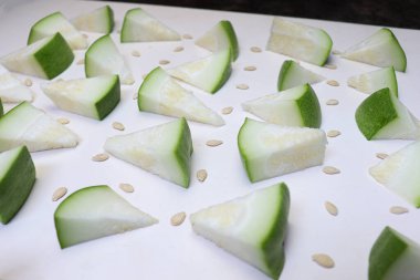 Beyaz arkaplanda tohumları olan balmumu kabağı dilimi