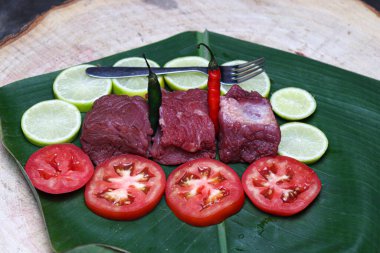fresh tasty cow beef with sliced lemon and spoon on banana leaf