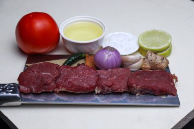 cow beef with spice and sliced lemon and tomato on chopping board