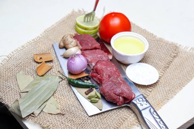 cow beef with spice and sliced lemon and tomato on chopping board
