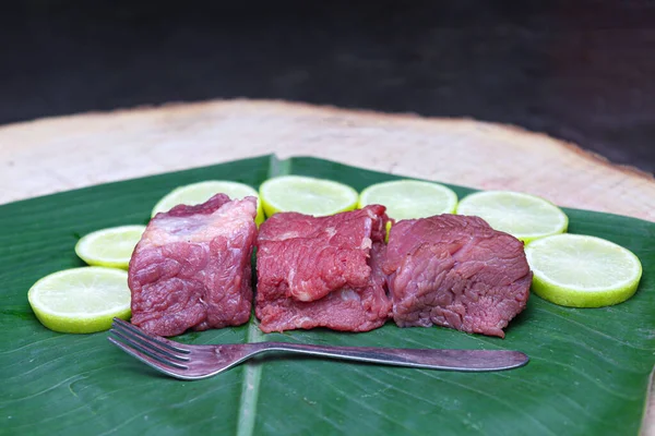 fresh tasty cow beef with sliced lemon and spoon on banana leaf