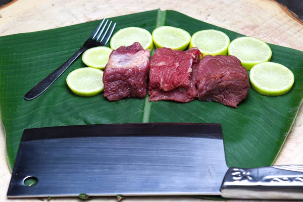 fresh tasty cow beef with sliced lemon and spoon on banana leaf