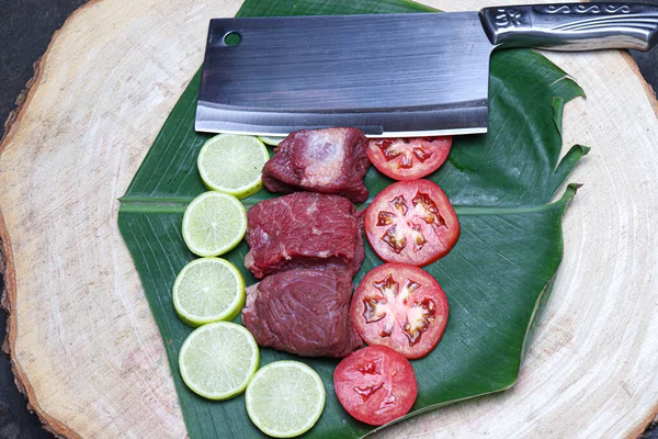 fresh tasty cow beef with sliced lemon and tomato on banana leaf