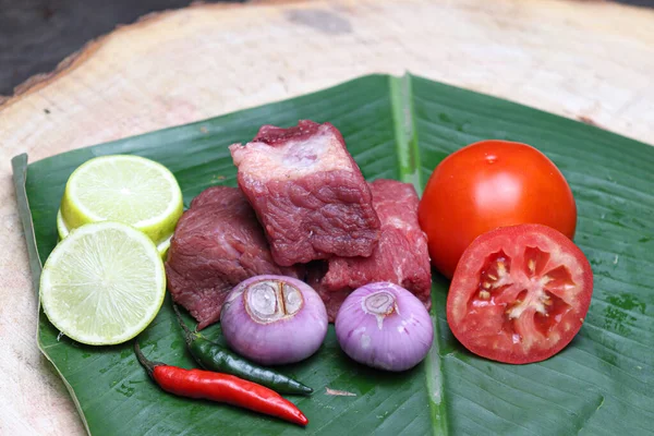 fresh tasty cow beef with sliced lemon and tomato on banana leaf