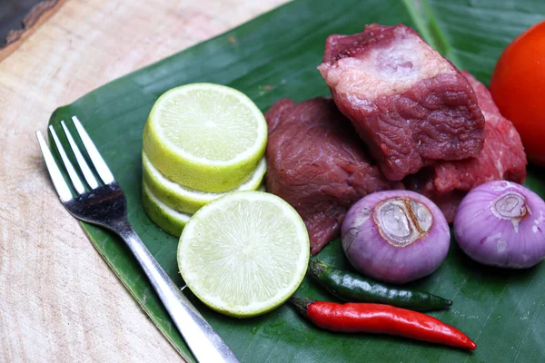 fresh tasty cow beef with sliced lemon and tomato on banana leaf