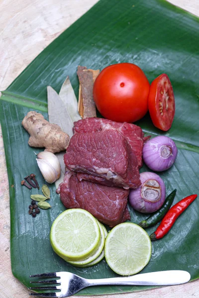 cow beef with spice and sliced lemon and tomato on banana leaf