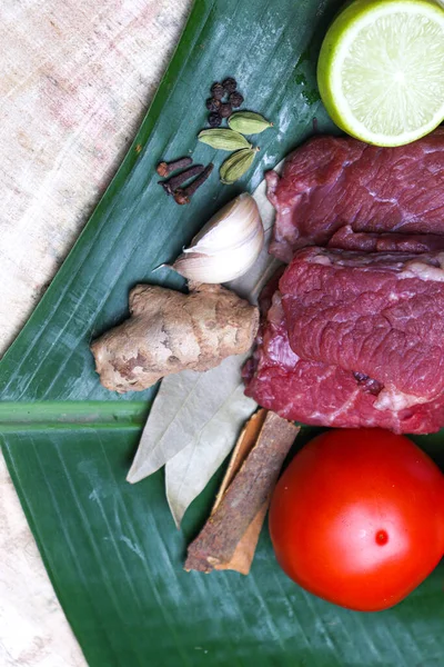 cow beef with spice and sliced lemon and tomato on banana leaf