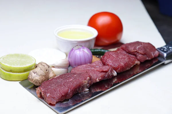 cow beef with spice and sliced lemon and tomato on chopping board