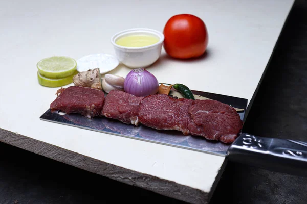 cow beef with spice and sliced lemon and tomato on chopping board