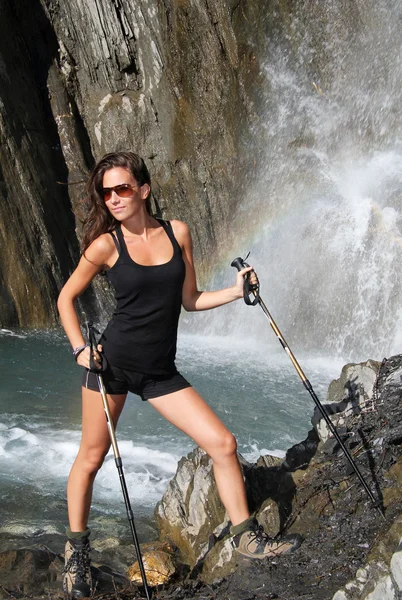 Schönes Mädchen posiert unterhalb des Bergwasserfalls — Stockfoto