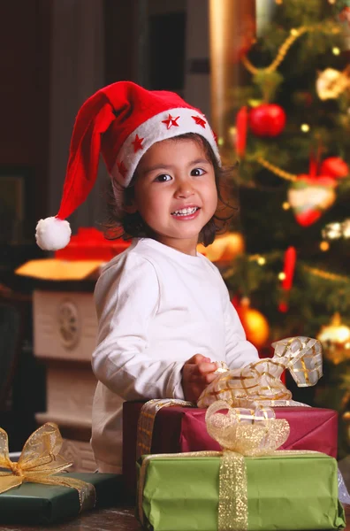 Sweet child smiles among Christmas gifts — Stock Photo, Image