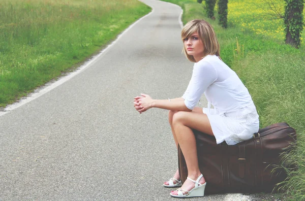 Hermoso modelo en una maleta en la frontera de una carretera —  Fotos de Stock