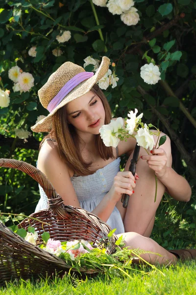 Jong meisje tuinieren onder witte rozen — Stockfoto