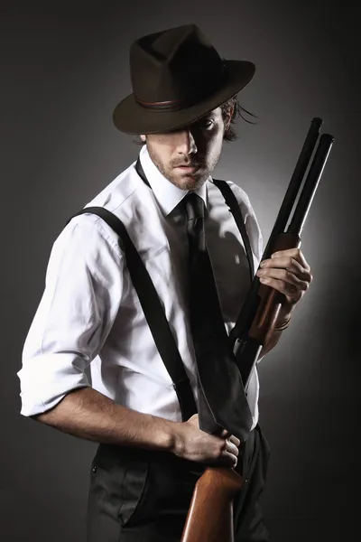 Yakışıklı gangster av tüfeği ve şapka ile poz Stok Resim