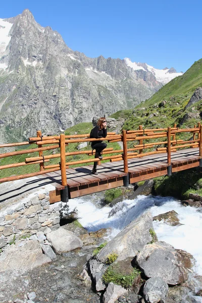 Hiking girl on a wooden mountain bridge — Stock Photo, Image