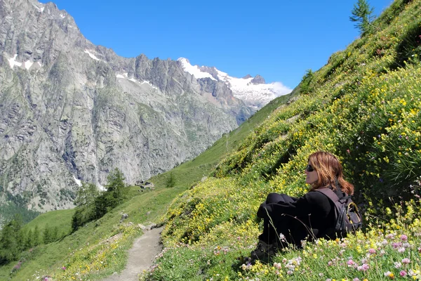 Hiking girl relaxing among mountain flowers — Stock Photo, Image