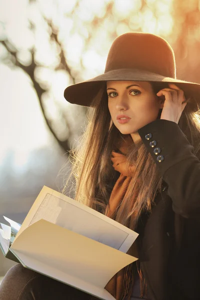 Elegant girl with a book in warm autumn light — Stock Photo, Image